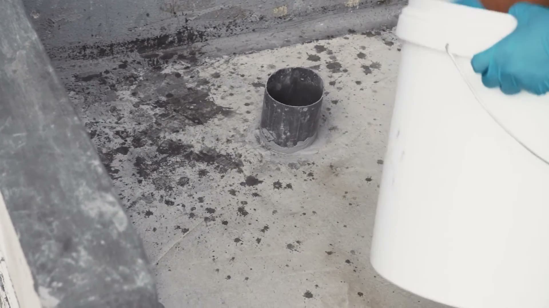 A bare concrete wet-area floor before waterproofing, dust on the slab and an open floor drain